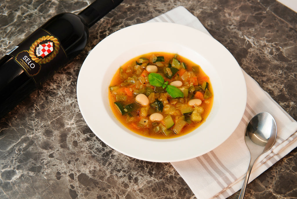 A bowl of creamy green Grah s Tikvicama soup, garnished with fresh parsley and a sprinkle of grated Parmesan, placed on a rustic wooden table.